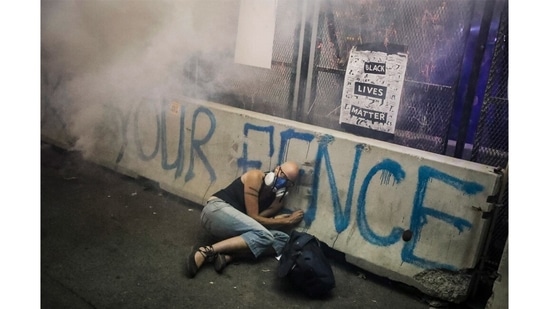 A demonstrator hides under a barrier as federal officers release tear gas during a Black Lives Matter protest at the Mark O. Hatfield United States Courthouse, July 29, 2020, in Portland, Oregon.(Marcio Jose Sanchez / AP Photo)