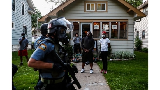 Bystanders watch as police walk down a street May 28, 2020, in St. Paul, Minneapolis. (John Minchillo / AP Photo)