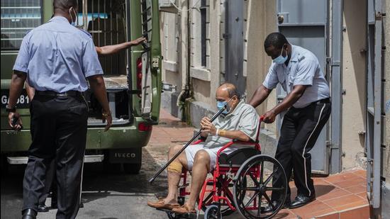 Mehul Choksi is taken to a police van in a wheelchair by a police officer after attending a court hearing, in Roseau, Dominica, earlier this week. (AP PHOTO.)