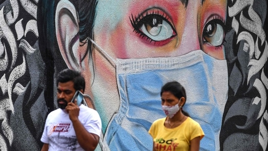Pedestrians walk past a wall mural representing awareness measures against the Covid-19 coronavirus, in Navi Mumbai. (AFP) Pedestrians walk past a wall mural representing awareness measures against the Covid-19 coronavirus, in Navi Mumbai. (AFP)