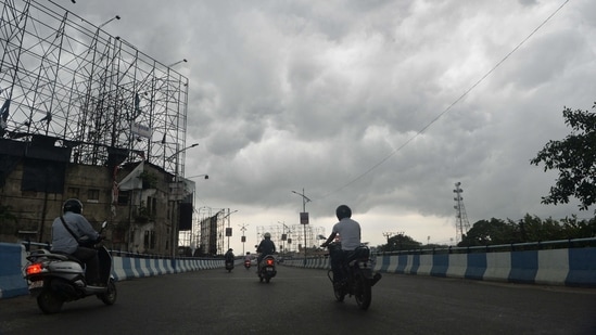 Motorists make their way along a road as dark monsoon clouds loom over Siliguri on June 11, 2021. (Diptendu DUTTA / AFP)