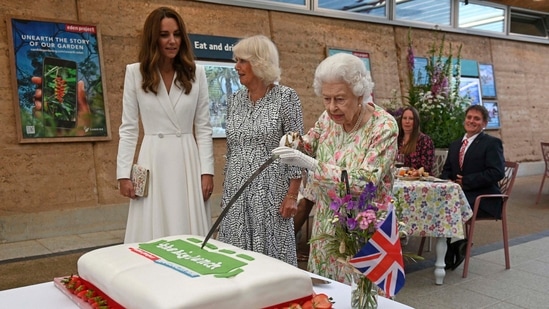 Britain's Queen Elizabeth II, centre, cuts a cake as Camilla, the Duchess of Cornwall, background centre and Kate, the Duchess of Cambridge stand by, as they attend an event in celebration of 'The Big Lunch 'initiative, during the G7 summit in Cornwall, England. (AP)