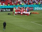 Denmark coach Kasper Hjulmand walks towards the Denmark players next to Christian Eriksen as he receives medical attention after collapsing during the match.