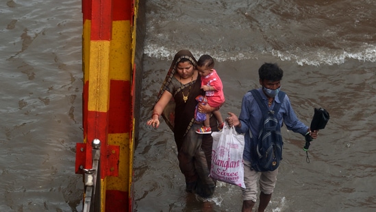 People and vehicles wade through a waterlogged road at King's Circle, in Mumbai. (Satish Bate/HT Photo) People and vehicles wade through a waterlogged road at King's Circle, in Mumbai. (Satish Bate/HT Photo)