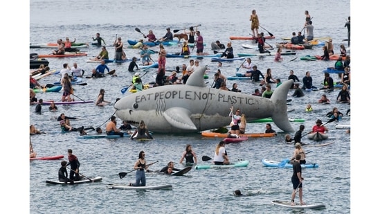 People riding kayaks and boards around a prop shark in a protest in Gyllyngvase beach, Falmouth, during the G7 summit in Cornwall on June 12.(Toby Melville / REUTERS)