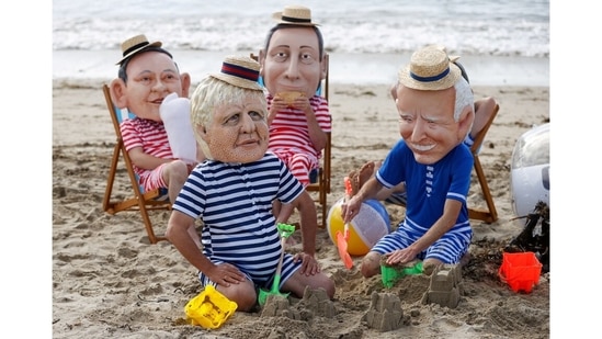 Oxfam activists wearing papier mache heads depicting Japan's Prime Minister Yoshihide Suga, Britain's Prime Minister Boris Johnson, Italy's Prime Minister Mario Draghi and US President Joe Biden perform during a protest at Swanpool Beach near Falmouth, during the G7 summit, in Cornwall on June 12.(Phil Noble / REUTERS)