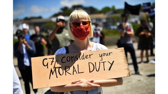 A demonstrator holding a placards as "Stop the War" and climate change activists protest in Hayle, during the G7 summit, in Cornwall on June 12. Despite a raft of recent climate pledges by G7 and other countries, campaigners want more detailed plans to be implemented quicker alongside greater aid for poorer nations.(Dylan Martinez / REUTERS)