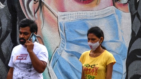 Pedestrians walk past a wall mural representing awareness measures against the Covid-19 coronavirus, in Navi Mumbai. Pedestrians walk past a wall mural representing awareness measures against the Covid-19 coronavirus, in Navi Mumbai.