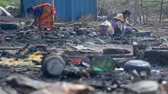 Rohingya refugees look for their belongings amid the charred remains of their camp following a fire incident that broke out earlier today in New Delhi.(AFP)