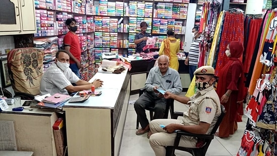 A Delhi Police personnel distributes face masks inside a garment store, in New Delhi on June 13. Weddings too cannot be held in public halls and only 20 people have been allowed to attend.(ANI)
