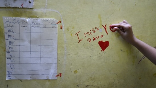 Kalpana Sinha's daughter, Deepika, 10, scribbles "I miss you papa" on a wall at their residence in New Delhi on May 9. She lost her father to Covid-19 less than a month ago and is trying to get her life back to normal, but her mother Kalpana told PTI, "nothing will ever be normal again."(Arun Sharma / PTI)
