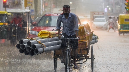 A man rides a cart during heavy rainfall.