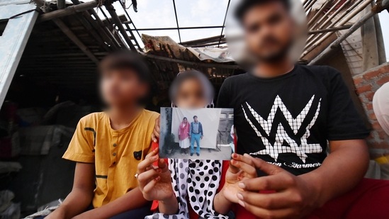 Three siblings -- aged nine, 11 and 13- show photographs of their parents, who died during the second wave of coronavirus, in New Delhi on May 5. To make things worse, their landlord refused to let their tenancy continue unless they paid rent. Their uncle, a welder, came to the children's rescue and took the three in.(Arun Sharma / PTI)