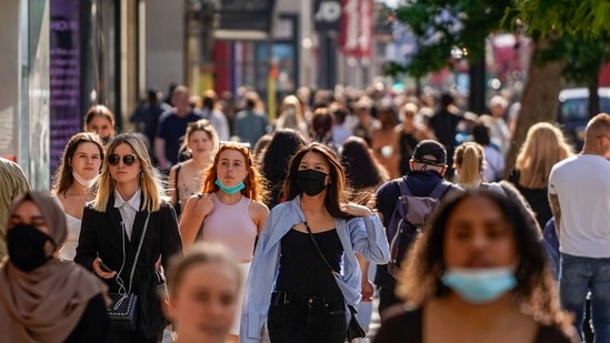Pedestrians, some wearing face coverings due to Covid-19, walk past shops on Oxford Street in central London.(AFP)
