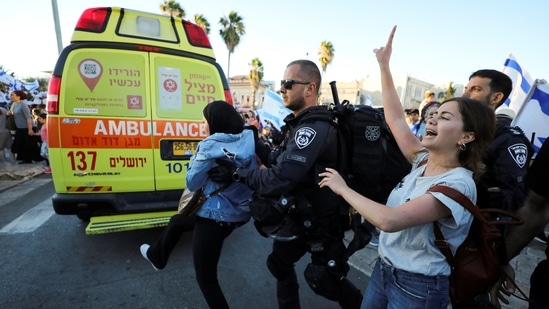 Israeli police remove a Palestinian woman from the area as youth from far-right Israeli groups participate in a flag-waving procession. (Reuters)