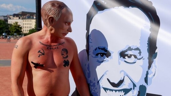 A protester wearing a mask of Russian President Vladimir Putin looks at a poster of Alexei Navalny ahead of a meeting between US President Joe Biden and Russian President Vladimir Putin in Geneva, Switzerland, June 15, 2021. (REUTERS)