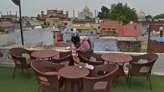 A worker cleans the sitting area of a rooftop restaurant in the backdrop of the Taj Mahal, in Agra on June 15.(Pawan Sharma / AFP)
