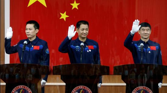 Astronauts Nie Haisheng, Liu Boming and Tang Hongbo wave as they meet members of the media behind a glass wall before the Shenzhou-12 mission to build China's space station, at Jiuquan Satellite Launch Center near Jiuquan, Gansu province. (REUTERS)