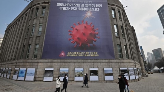 Pedestrians walk past a poster depicting the coronavirus, at the City Hall in Seoul, South Korea. (AFP for representation) Pedestrians walk past a poster depicting the coronavirus, at the City Hall in Seoul, South Korea. (AFP for representation)