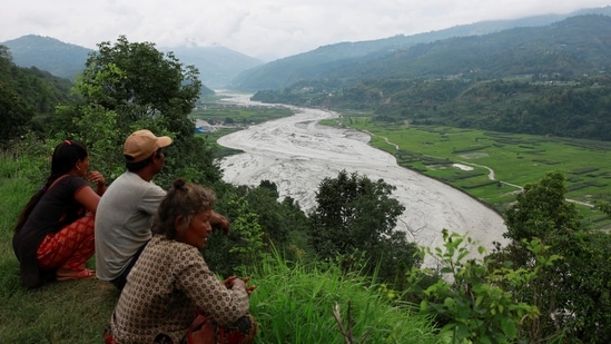 People from a hilltop view the swollen Melamchi river in Sindhupalchok, on June 16. The flash floods in Sindhupalchok district, which touches Tibet on the Northern side, are suspected to be triggered by a glacial outburst that has dumped a large mass of mud, stones and residues in the Melamchi Corridor.(Navesh Chitrakar / REUTERS)