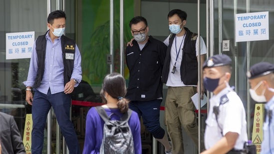 Cheung Chi-wai, deputy editor at the Apple Daily newspaper, center, is escorted from the publication's headquarters building by officers with the Hong Kong Police Force's national security department in Hong Kong, China, on Thursday. (Bloomberg) Cheung Chi-wai, deputy editor at the Apple Daily newspaper, center, is escorted from the publication's headquarters building by officers with the Hong Kong Police Force's national security department in Hong Kong, China, on Thursday. (Bloomberg)