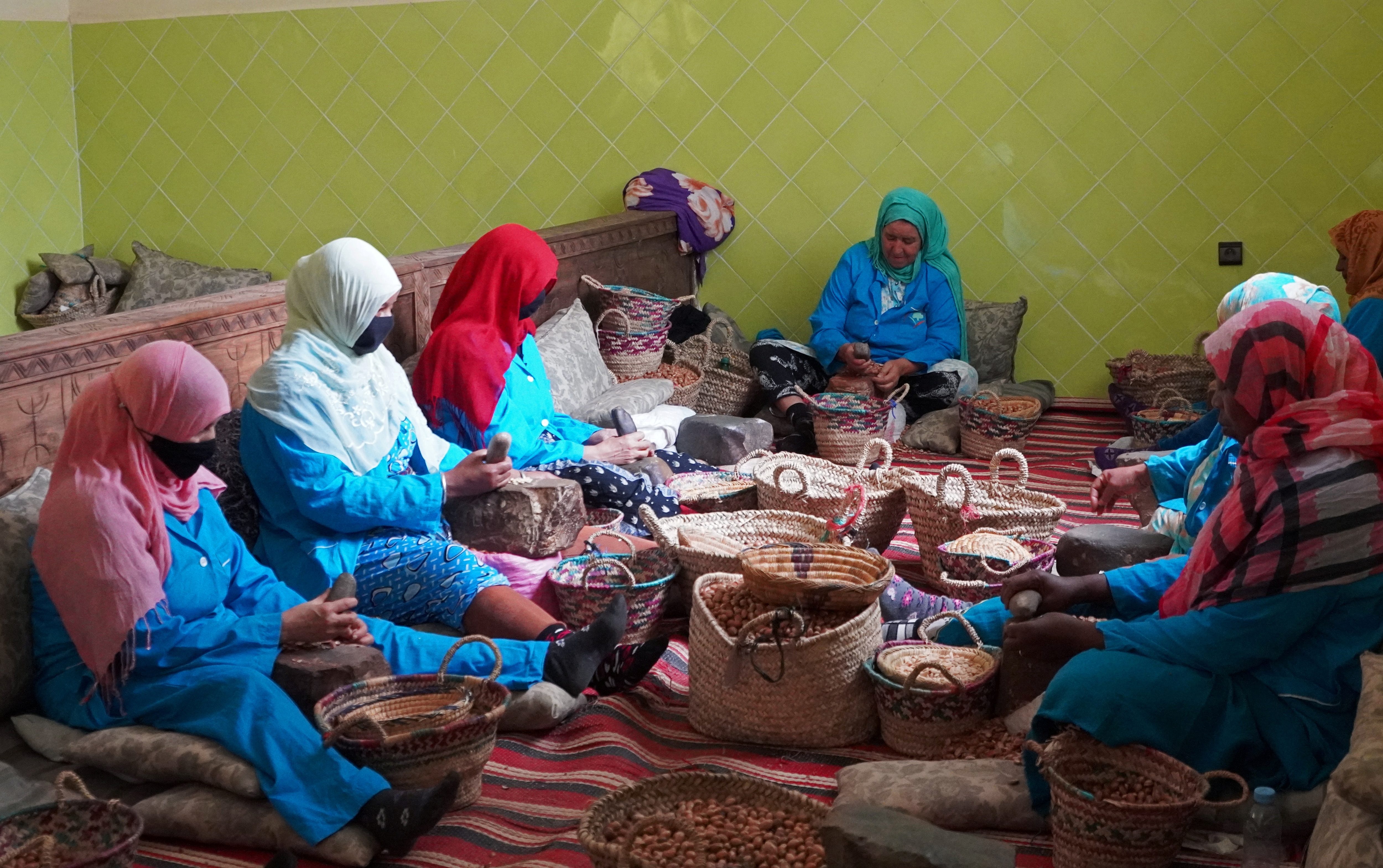 Amazigh women sit together as they crush argan nuts to extract the kernels, at Women's Agricultural Cooperative Taitmatine, in Tiout, near Taroudant, Morocco June 10, 2021. (REUTERS)