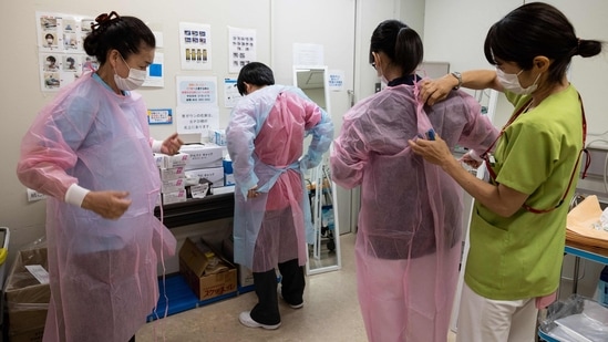 Cleaners from Pegasus Corporation put on protective suits before entering the Covid-19 ward at St. Marianna University Kawasaki Municipal Tama Hospital in Kawasaki, Japan on June 15. While the number of new cases and deaths have abated in countries like the United States and Britain, several nations are experiencing vaccine shortages as the Delta variant becomes the dominant strain around the world.(Yuki Iwamura / AFP)