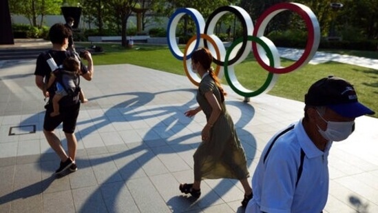 FILE - People walk near the Olympic Rings in Tokyo. (AP) FILE - People walk near the Olympic Rings in Tokyo. (AP)
