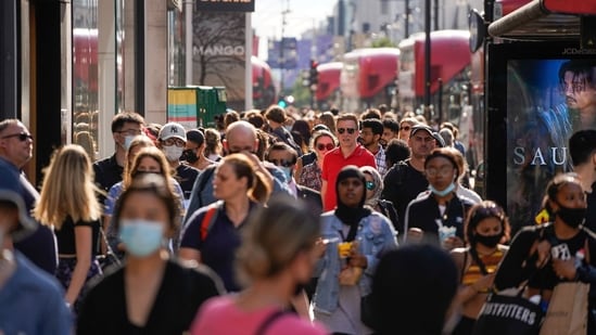 Pedestrians, some wearing face coverings due to Covid-19, walk past shops on Oxford Street in central London.(AFP)