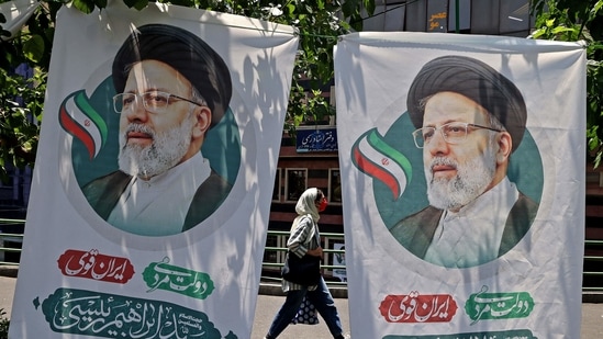 An Iranian woman walks past banners of ultraconservative cleric and presidential candidate Ebrahim Raisi, in Tehran, on June 17, 2021, on the eve of the Islamic republic's presidential election. (ATTA KENARE / AFP)