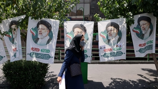 An Iranian woman walks past banners of ultraconservative cleric and presidential candidate Ebrahim Raisi, in Tehran, on June 17, 2021, on the eve of the Islamic republic's presidential election. (Photo by ATTA KENARE / AFP)(AFP)