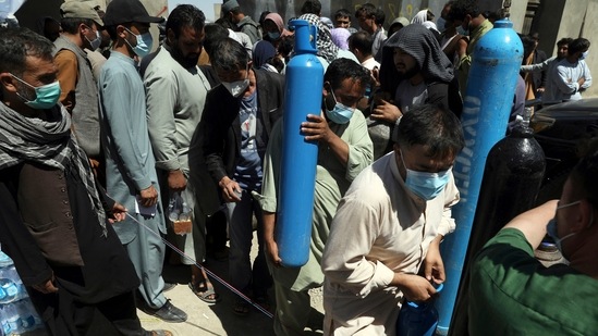 A man carries an oxygen cylinder from a privately owned oxygen factory, in Kabul, Afghanistan, as Covid surge worsens.(AP)