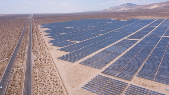 An aerial image shows vehicles driving on the California 14 Highway as solar panels, part of an electricity generation plant, stand on June 18 in Kern County near Mojave, California. The California ISO, which oversees the state's power generation, extended a Flex Alert asking customers to conserve electricity amid concerns of power outages during the heat wave.(Patrick T. Fallon / AFP)