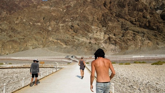Visitors walk by the salt flats of Badwater Basin inside Death Valley National Park on June 17 in Inyo County, California. The heat comes from a high pressure system over the West, a buckle in the jet stream winds that move across the US and vast swaths of soil sucked dry by a historic drought, Marvin Percha, a senior meteorologist for the National Weather Service in Phoenix told AP.(Patrick T. Fallon / AFP)
