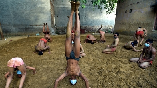 Wrestlers in an akhada performing yoga on the eve of International Yoga Day, at Sarfabad village, in Noida. (Sunil Ghosh / Hindustan Times)