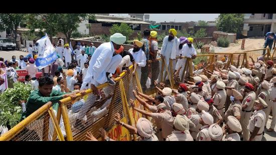 The party workers scaling the barricades put up by police outside the minister’s house in Sangrur on Tuesday. (HT Photo) The party workers scaling the barricades put up by police outside the minister’s house in Sangrur on Tuesday. (HT Photo)