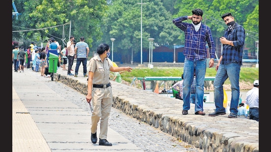 A police officer warns two men flouting social distancing norms at Sukhna Lake in Chandigarh on Thursday. (Ravi Kumar/HT)