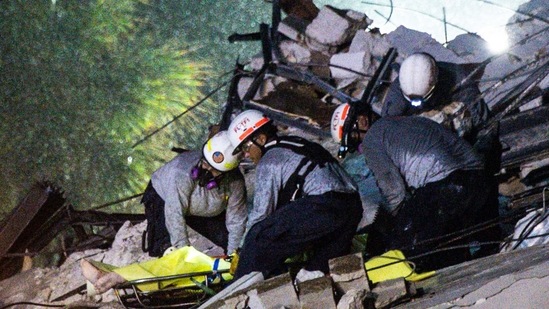 Search and Rescue personnel pull out a body out of the rubble after the partial collapse of the Champlain Towers South in Surfside on June 24. Authorities said they were still without news of 99 people who may have been inside the building with 102 others having been accounted for, according to Miami-Dade Mayor Daniella Levine Cava.(Chandan Khanna / AFP)