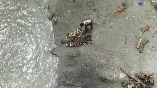 A municipal corporation worker cremates the body of a person who was buried in a shallow grave on the banks of Ganga river during the Covid-19 pandemic, near Phaphamau Ghat, in Prayagraj, on June 25. India is at the same time also nearing the grim milestone of 400,000 total deaths due to the disease, with 1,183 new deaths recorded on June 26.(Sanjay Kanojia / AFP)