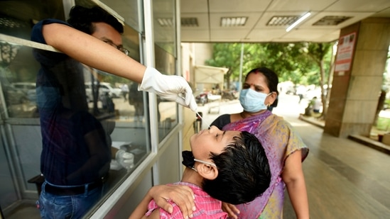 A health worker collects a swab sample from a child to test for Covid-19 infection, at Sector 30 district hospital in Noida on June 24. The health ministry data further showed that the number of active cases has declined to 595,565, or 2.03% of the total cases.(Sunil Ghosh / HT Photo)