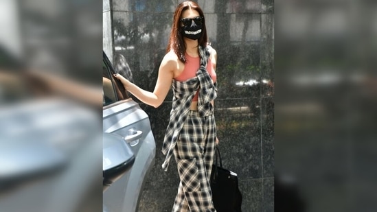 Kriti chose a coral coloured halter neck crop top for the outing. The actor flaunted her toned midriff in it. She layered a check print oversized shirt over the top and did so in a quirky way. (Varinder Chawla) Kriti chose a coral coloured halter neck crop top for the outing. The actor flaunted her toned midriff in it. She layered a check print oversized shirt over the top and did so in a quirky way. (Varinder Chawla)
