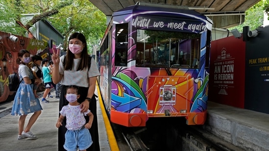 Passengers pose next to a Peak Tram on June 16, 2021. Hong Kong’s Peak Tram is a fixture in the memories of many residents and tourists, ferrying passengers up Victoria Peak for a bird’s eye view of the city’s many skyscrapers. (AP)