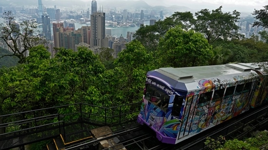 A Peak Tram passes an uphill of the Victoria Peak with a backdrop of Hong Kong on June 17, 2021. (AP)
