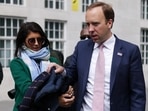 Britain's Health Secretary Matt Hancock hands his coat to his aide Gina Coladangelo (L) before a television interview outside BBC's Broadcasting House in London, Britain, May 16, 2021. 