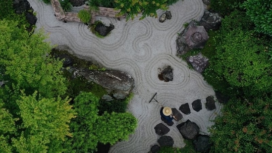 A gardener makes wave-shaped patterns, known as 'samon', at Karesansui, a traditional Japanese Dry Landscape, at Takao Komagino Garden in Hachioji on the outskirts of Tokyo, on June 7. Tokyo is never boring. It has survived earthquakes and war. It will survive the coronavirus.(Kim Kyung-Hoon / REUTERS)