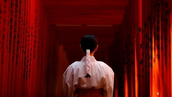 Shouko Totsuka, a Miko also known as a shrine maiden, stands for a photograph inside the tunnel of Red Torii Gate at the Hie-Jinja Shinto Shrine in Tokyo on June 1. Light and shadows are the hallmarks of Olympic Games, the second time Tokyo is the host.(Kim Kyung-Hoon / REUTERS)