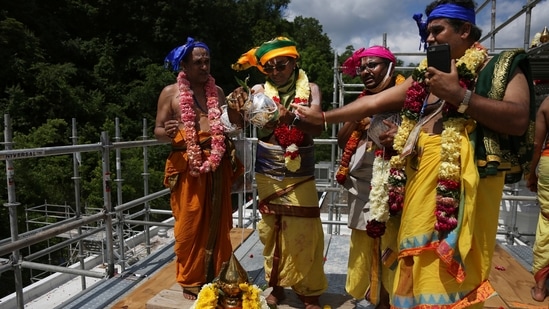 Priests, from left, Sri Ranganathan, Temple head priest Sri Samudrala Venkatacharyulu, Sri Kannan Srinivasan and Sri Rangarajan pour holy waters onto a spire known as a kalasham atop the gopuram, an ornamented temple tower, during the Hindu rededication ceremony.(AP) Priests, from left, Sri Ranganathan, Temple head priest Sri Samudrala Venkatacharyulu, Sri Kannan Srinivasan and Sri Rangarajan pour holy waters onto a spire known as a kalasham atop the gopuram, an ornamented temple tower, during the Hindu rededication ceremony.(AP)