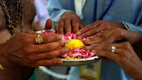 Hindu priest Gopala Dhattar, left, gives blessings to Pandu Tadikamalla, center, and his wife, Rama Tadikamalla, right, as they rest their hands on a bed of flower petals during the Maha Kumbhabhishekam.(AP) Hindu priest Gopala Dhattar, left, gives blessings to Pandu Tadikamalla, center, and his wife, Rama Tadikamalla, right, as they rest their hands on a bed of flower petals during the Maha Kumbhabhishekam.(AP)