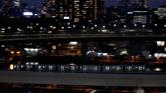 A Yurikamome line train, a driverless automatic train system, travels past buildings in Tokyo on April 21. In April 2020, the trains glided through Tokyo with most seats empty. Residents were asked to stay home as the pandemic swept through Japan and the world. The Olympics had been postponed a month earlier.(Kim Kyung-Hoon / REUTERS)