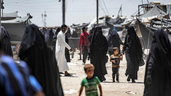 People walk about at the Kurdish-run al-Hol camp, which holds relatives of suspected Islamic State (IS) group fighters, in Hasakeh governorate in northeastern Syria, on June 23, 2021.(AFP)